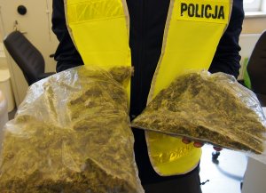 policjant trzyma w rękach worki z marihuaną